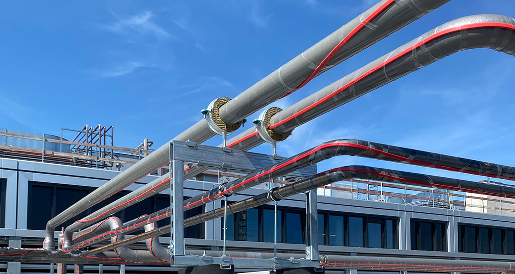 Installation mehrerer BISOFIX MW Kälterohrträger an Rohren, welche auf einem Flachdach aufgeständert wurden