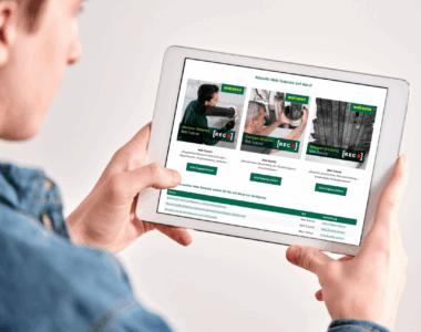 Ein Mann hält ein Tablet in der Hand, auf welchem ein Ausschnitt der Walraven Webseite zu sehen ist. Dort sind drei Bilder in einer Reihe ersichtlich, welche die Titelbilder für diverse Web-Tutorials darstellen, welche im Rahmen der Walraven-Akademie auf Abruf verfügbar sind.