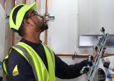 Heizungsinstallateur hält eine vormontierte RapidRail® Montageeinheit vor einer Rohrinstallation im Technikraum.