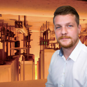 Titelbild des Walraven Webinars "Brandgeprüfte Montagesysteme für die Gebäudetechnik". Referent Toni Sebald ist vor einem Brandofen zu sehen, orange dominiert auf dem Bild. Im Brandofen werden gerade Montageschienen geprüft.