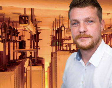 Titelbild des Walraven Webinars "Brandgeprüfte Montagesysteme für die Gebäudetechnik". Referent Toni Sebald ist vor einem Brandofen zu sehen, orange dominiert auf dem Bild. Im Brandofen werden gerade Montageschienen geprüft.