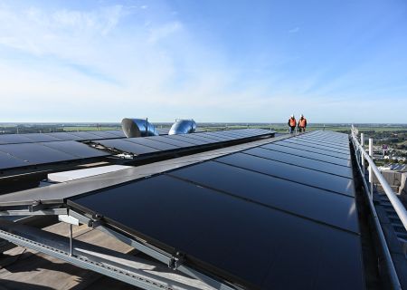 Solaranlage auf einem Walraven Gebäudedach mit zwei Mitarbeitenden bei der Begehung der Photovoltaikmodule.