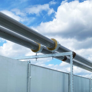 Montierte Kälterohrleitungen mit gedämmten Walraven Bisofix MW Kälterohrschellen auf Montageschienen zur energieeffizienten Befestigung gemäß Gebäudeenergiegesetz (GEG); im Hintergrund ein teilweise bewölkter Himmel.