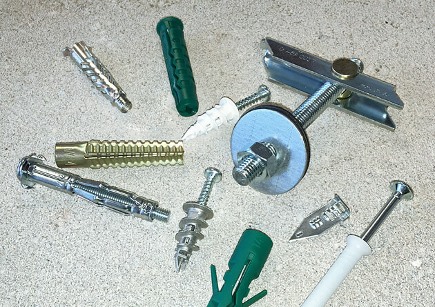 Verschiedene Dübel und Befestigungselemente aus Metall und Kunststoff zur Veranschaulichung unterschiedlicher Systeme und Anwendungen in der Dübeltechnik.